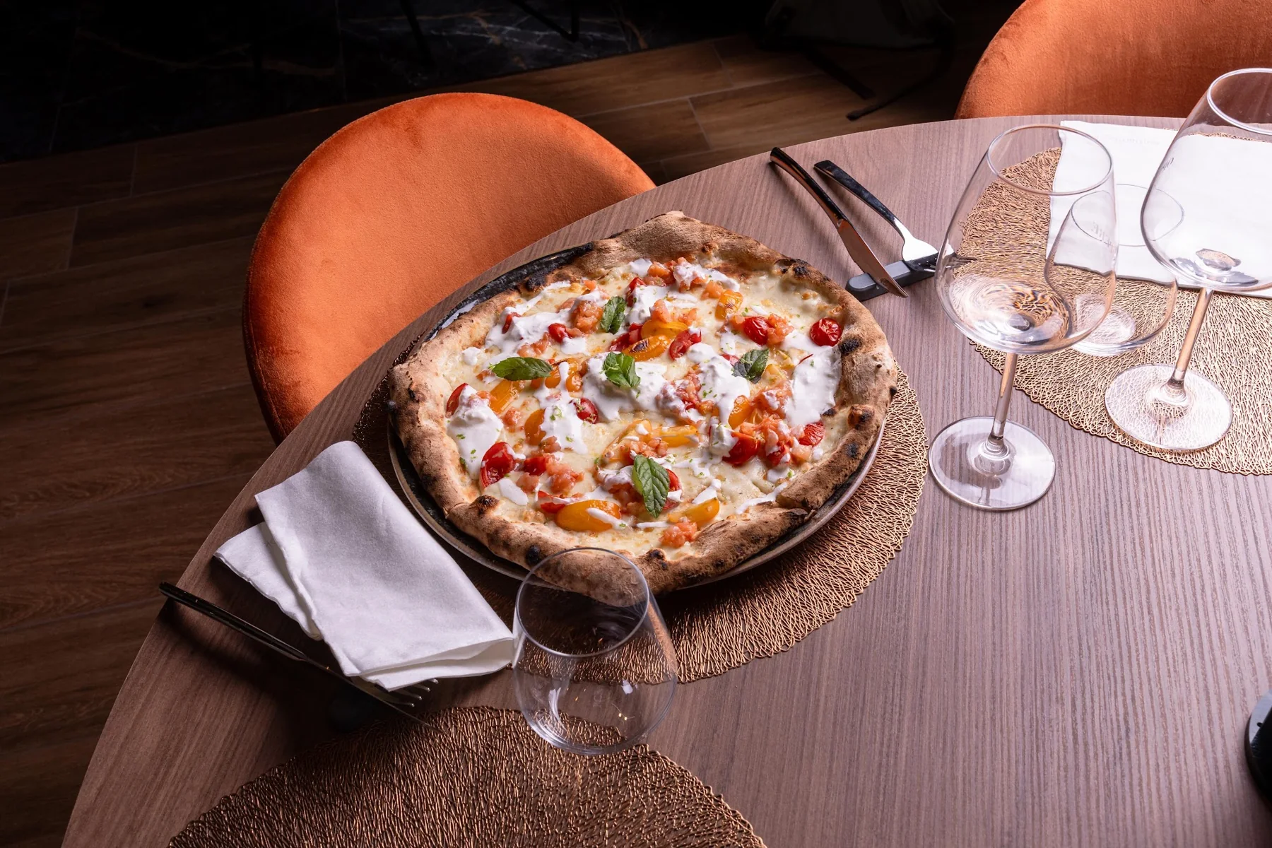 Una pizza Rogà a tavola, tra calici e sedute color terracotta